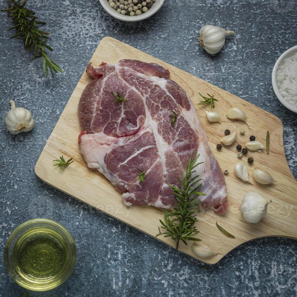 raw pork on cutting board with herbs and spices photo