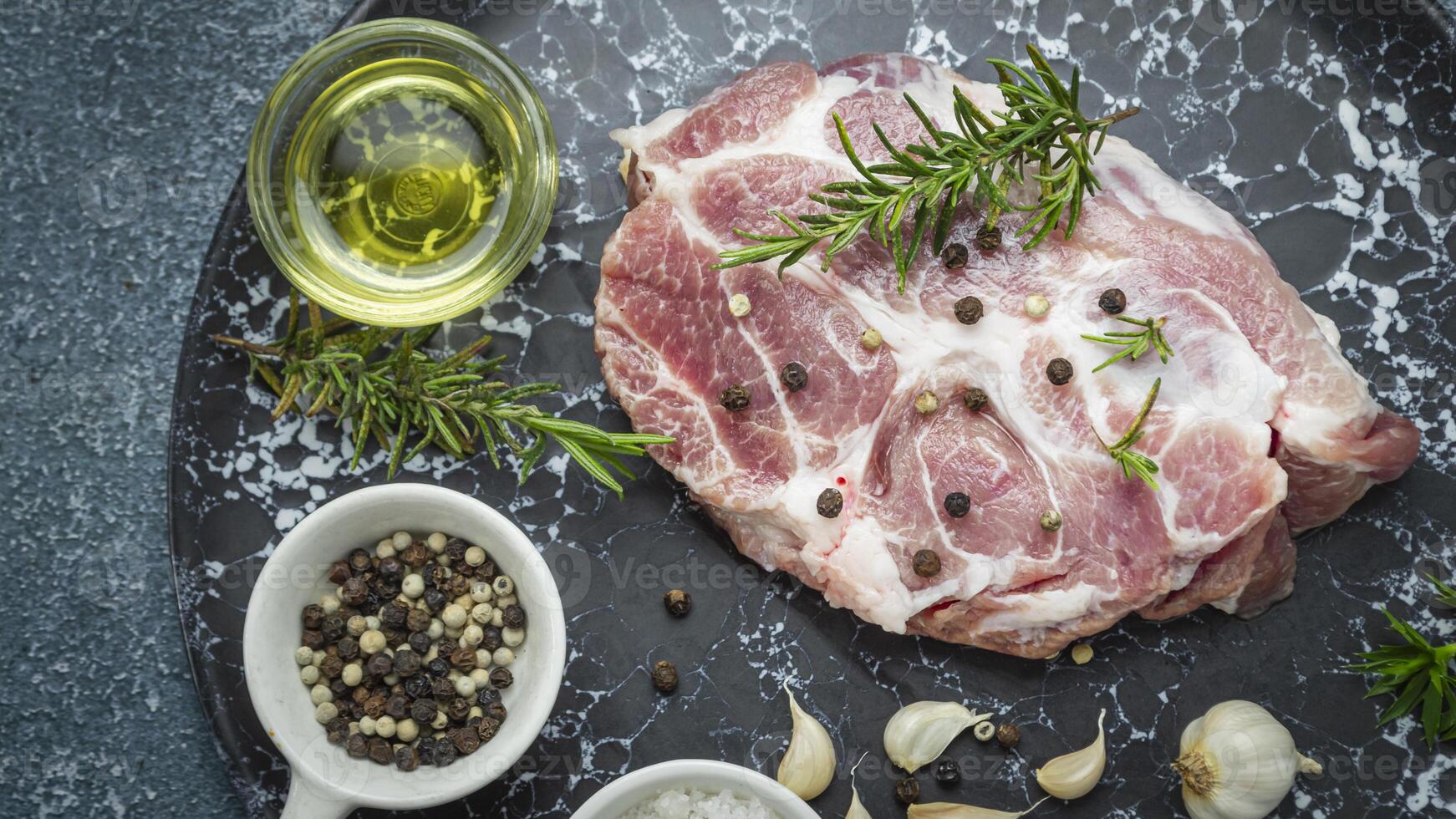 raw pork on a black plate with herbs and spices photo