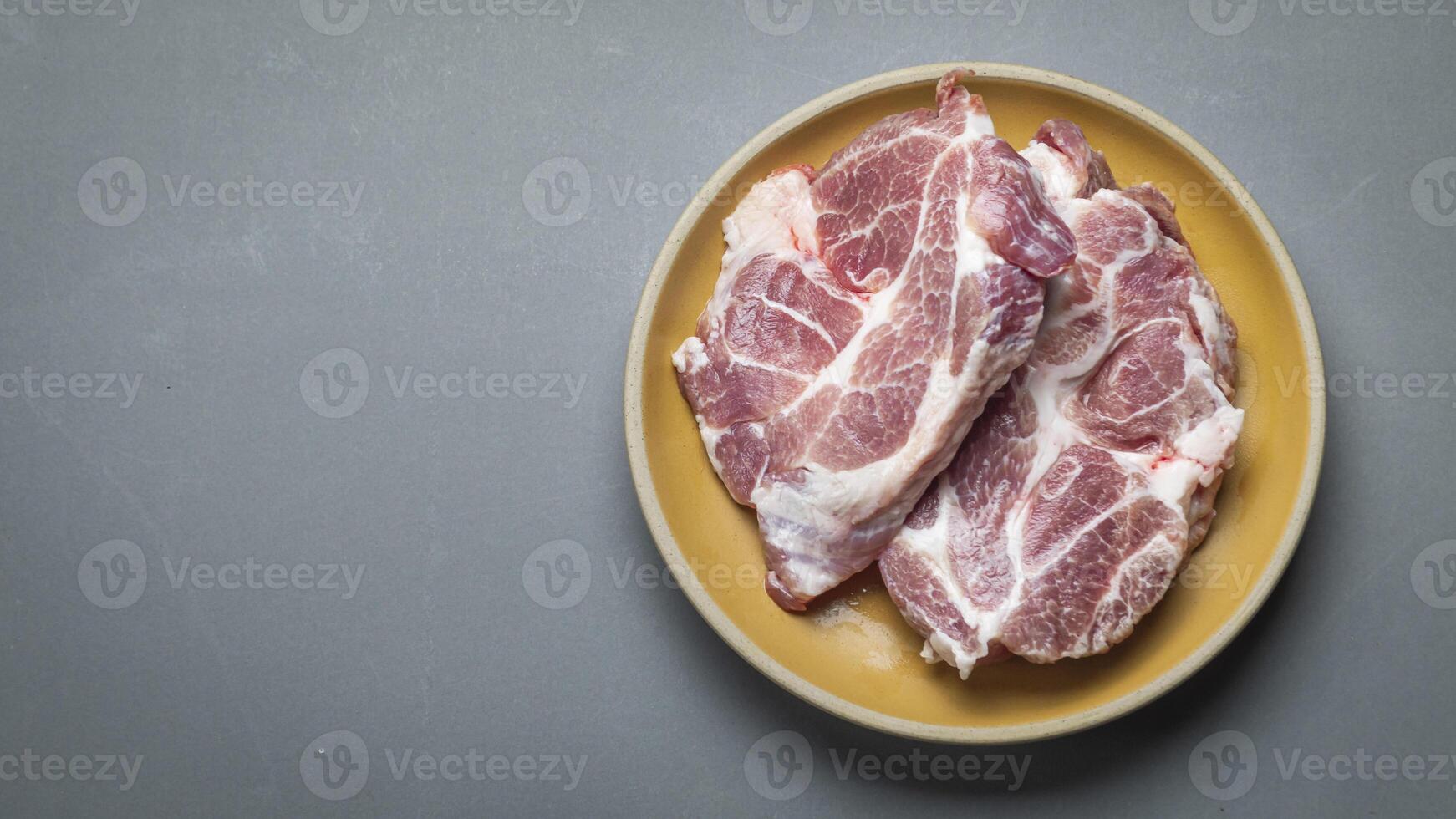 raw pork chops on a plate on a gray background photo