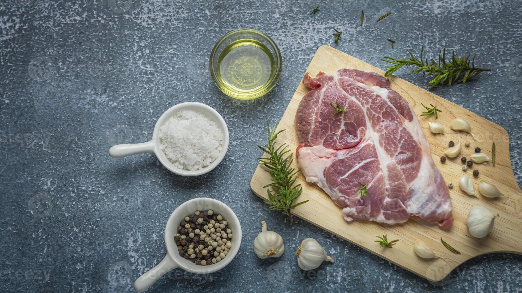 raw pork on cutting board with spices and herbs photo