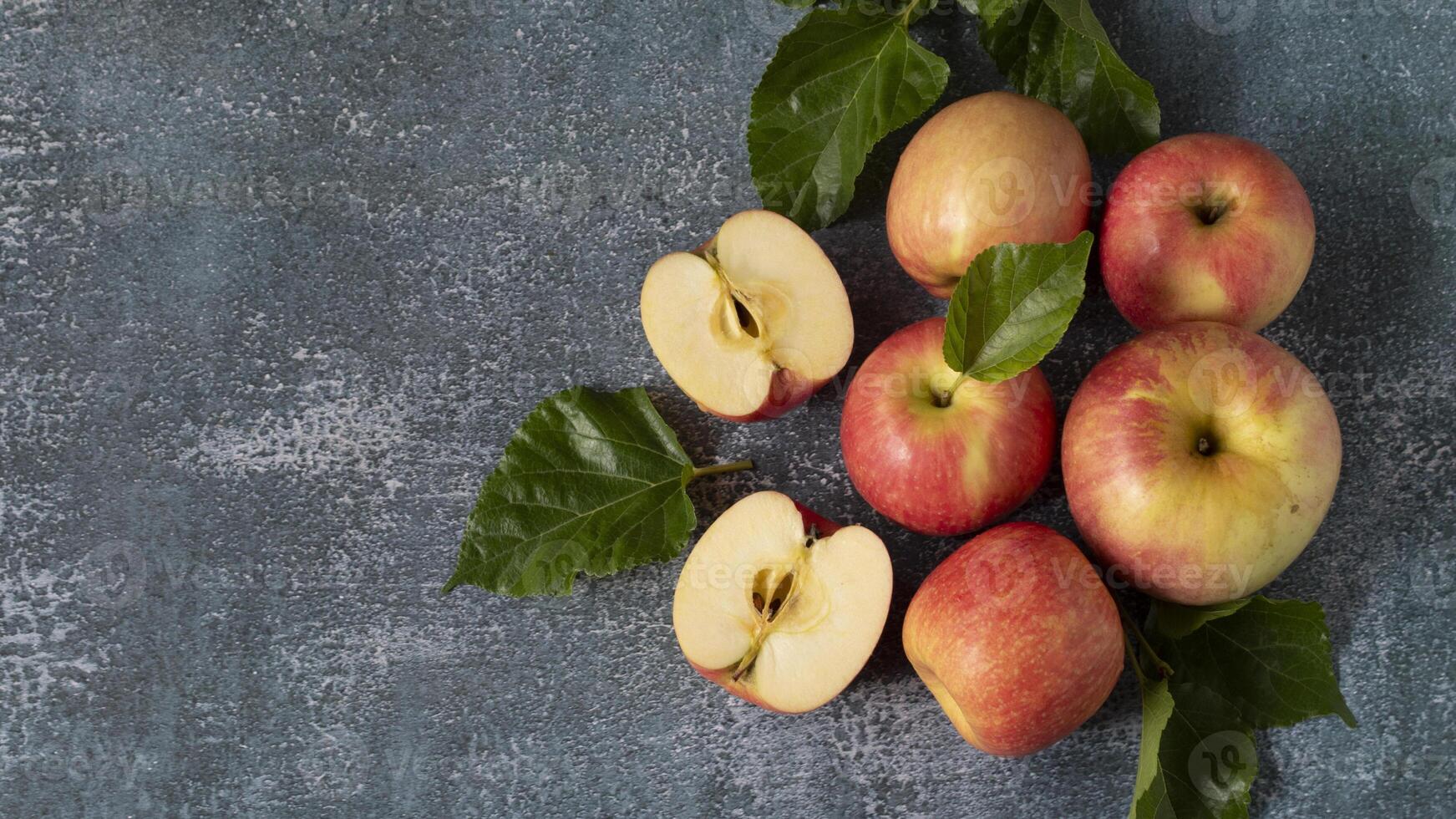 apples with leaves and slices on a dark surface photo