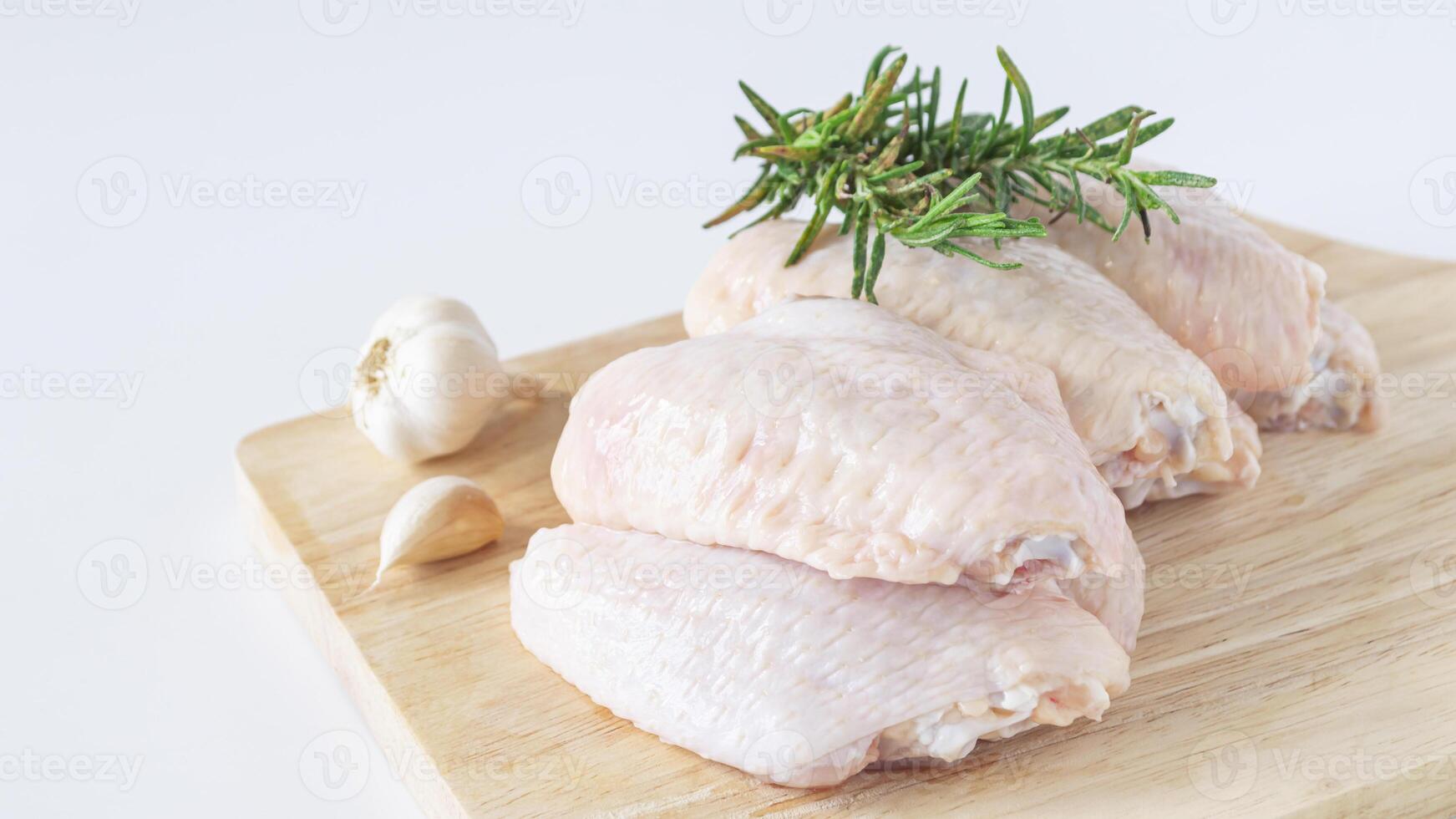 raw chicken on a cutting board with garlic and rosemary photo