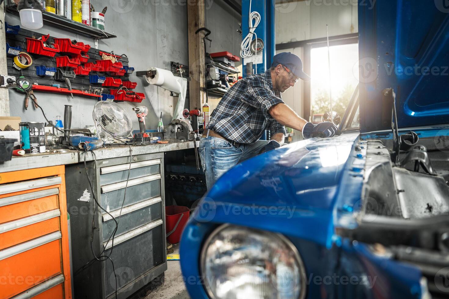 Mechanic Working on Classic Blue Car in Garage Workshop During Daytime photo