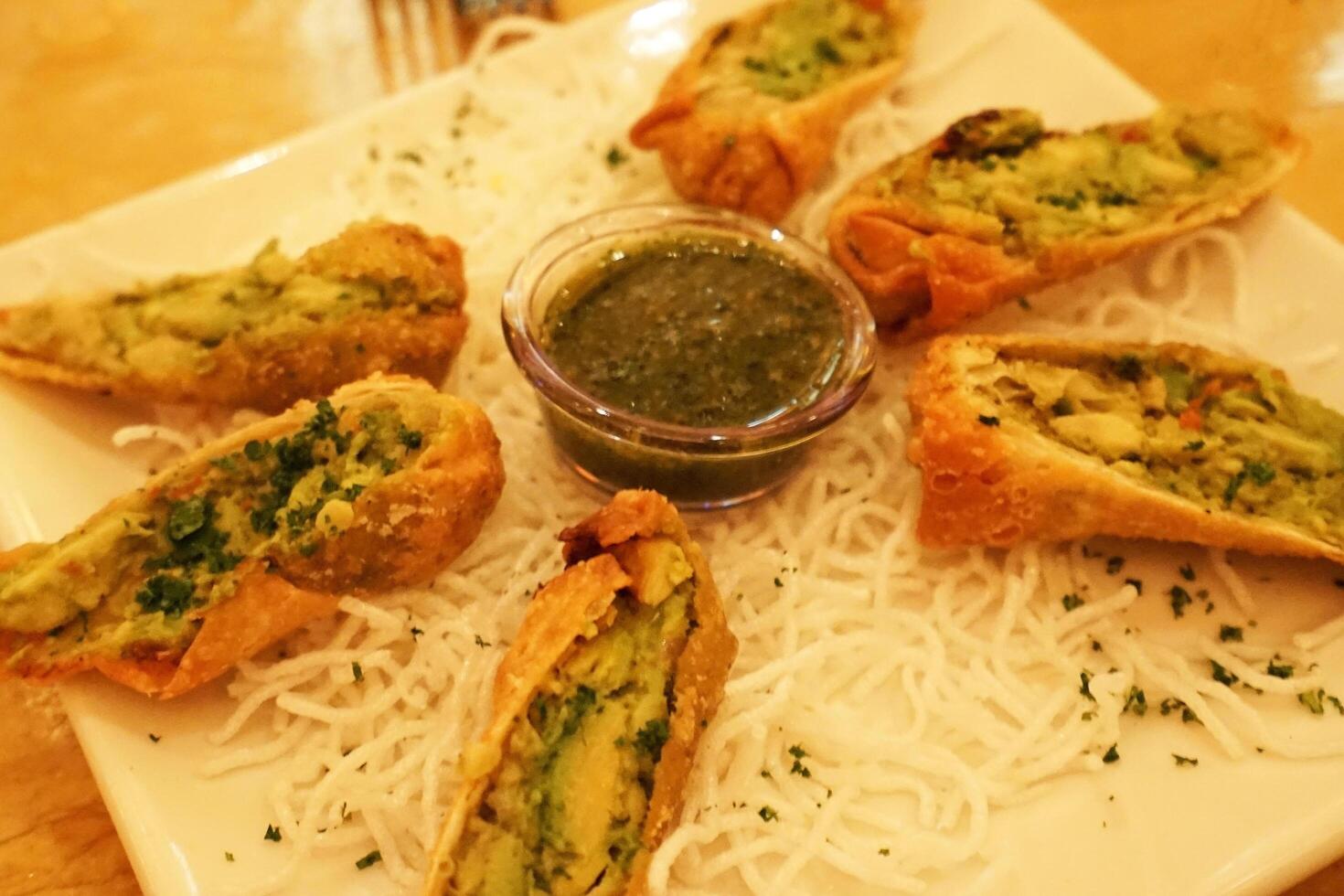Close up mixed deep fried spring rolls, variety of filled, rolled appetizer wrappers or dim sum found in Southeast Asian cuisine photo