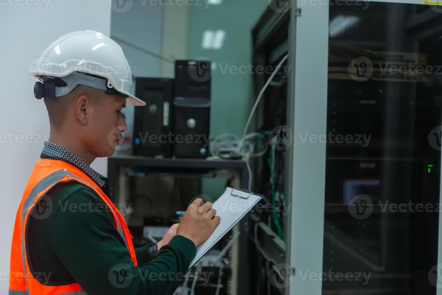 an asian adult IT technician working on network Internet cables and servers and try to checklist on the paper photo
