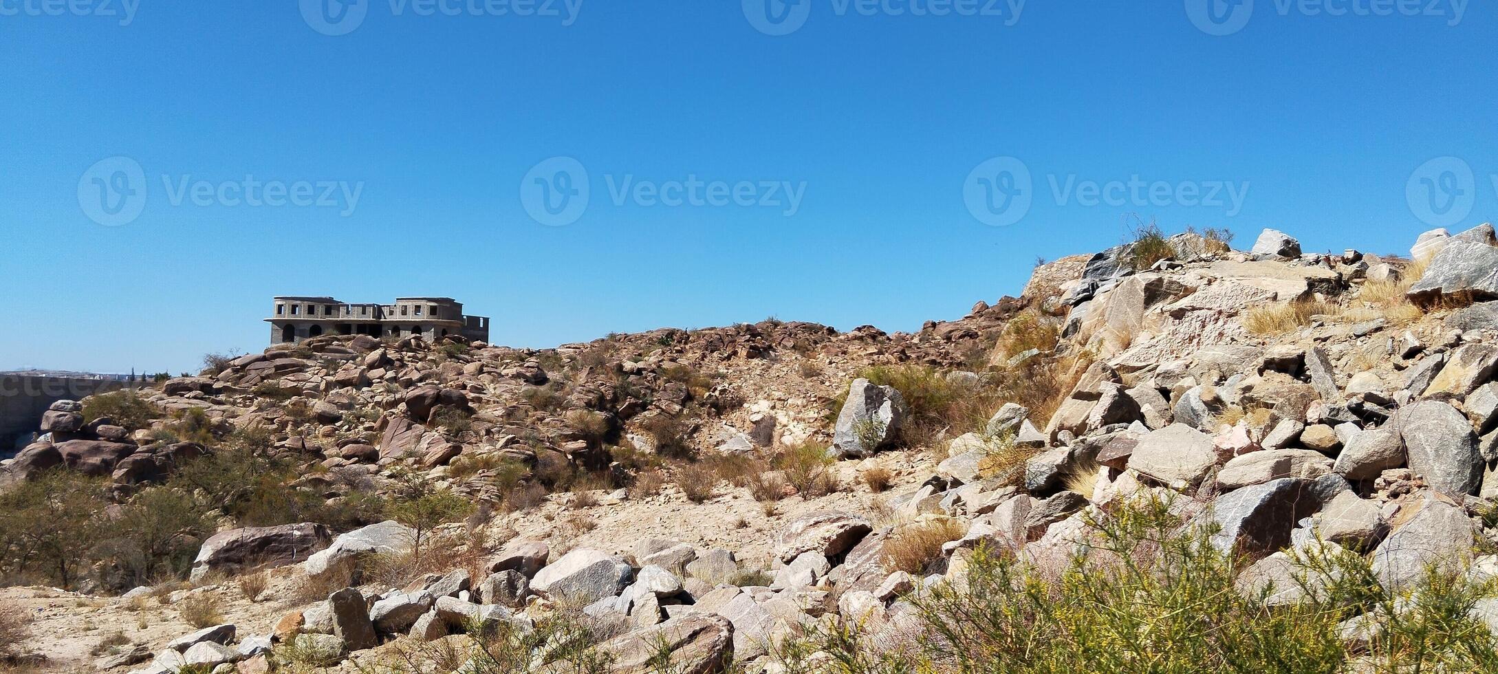 a rocky hill with rocks and bushes in the desert photo