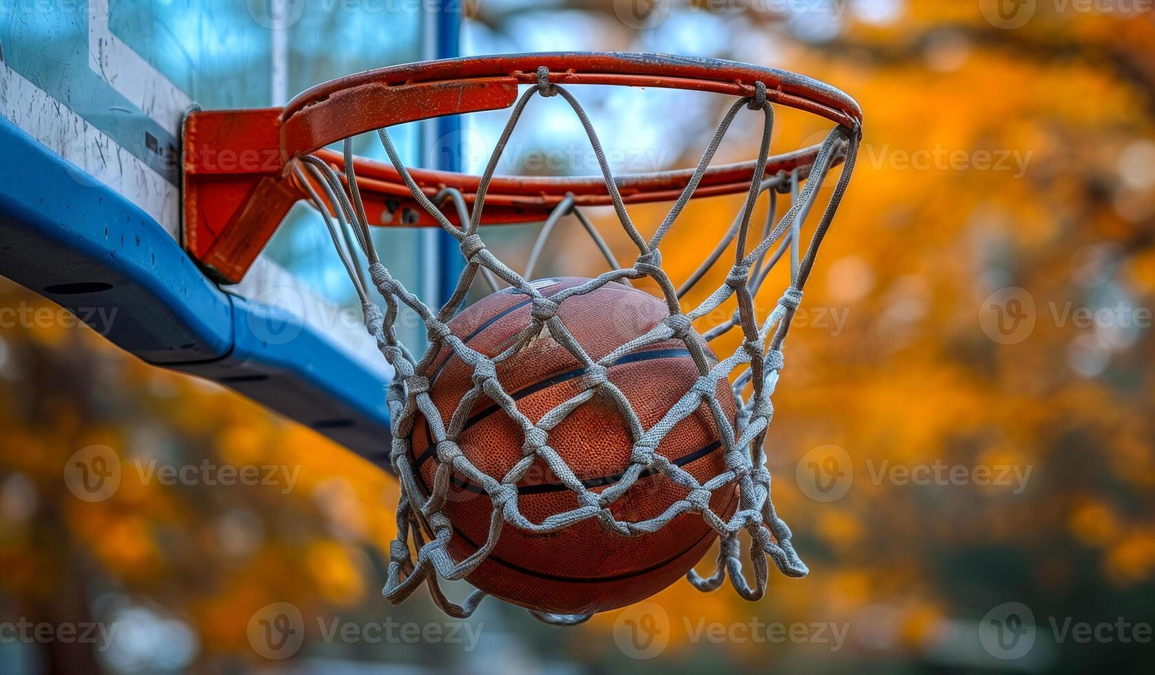 A basketball is hanging from a net in a basketball hoop. The ball is wet and he is frozen photo