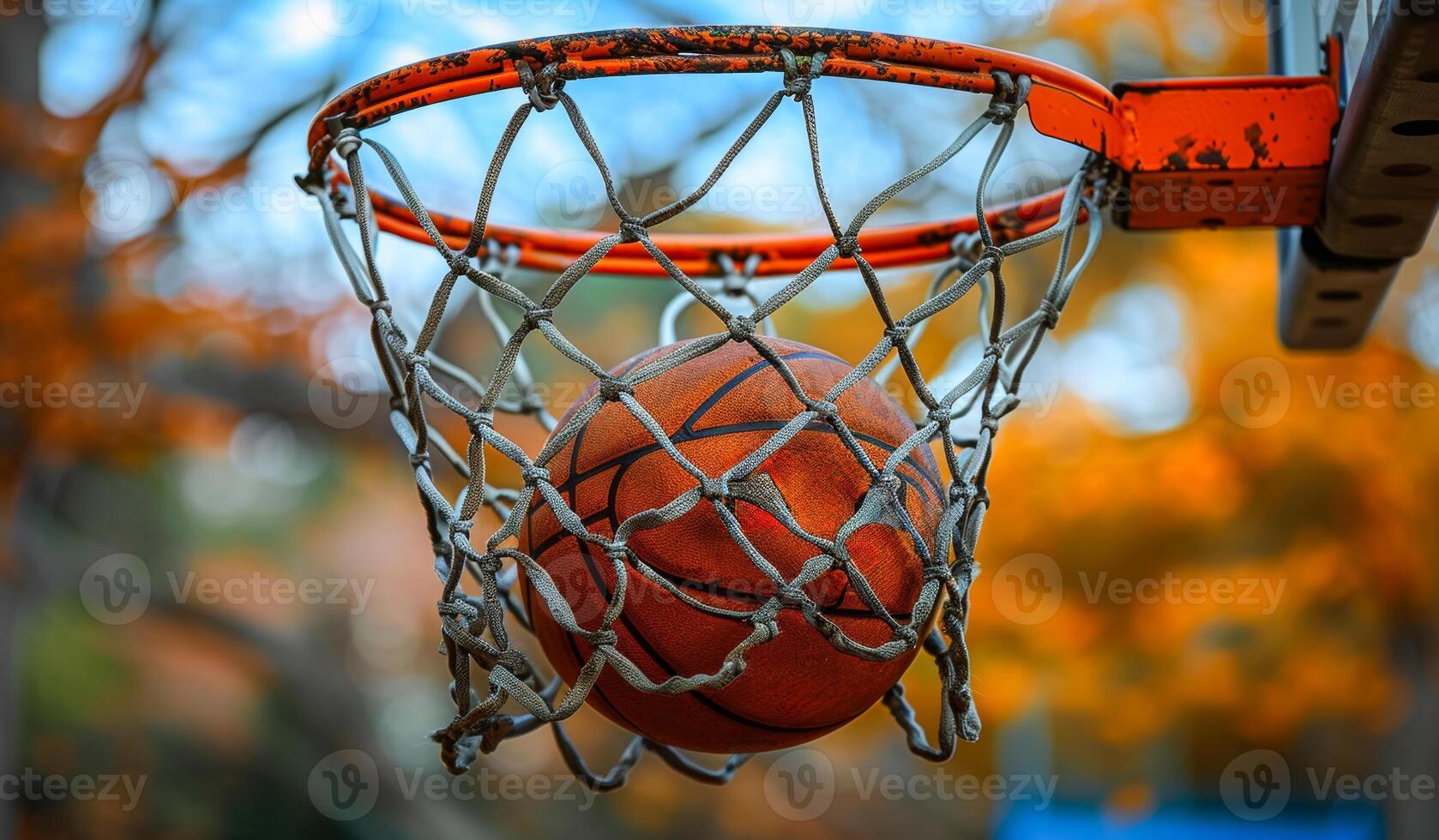 A basketball is hanging from a net. The net is orange and the ball is orange photo