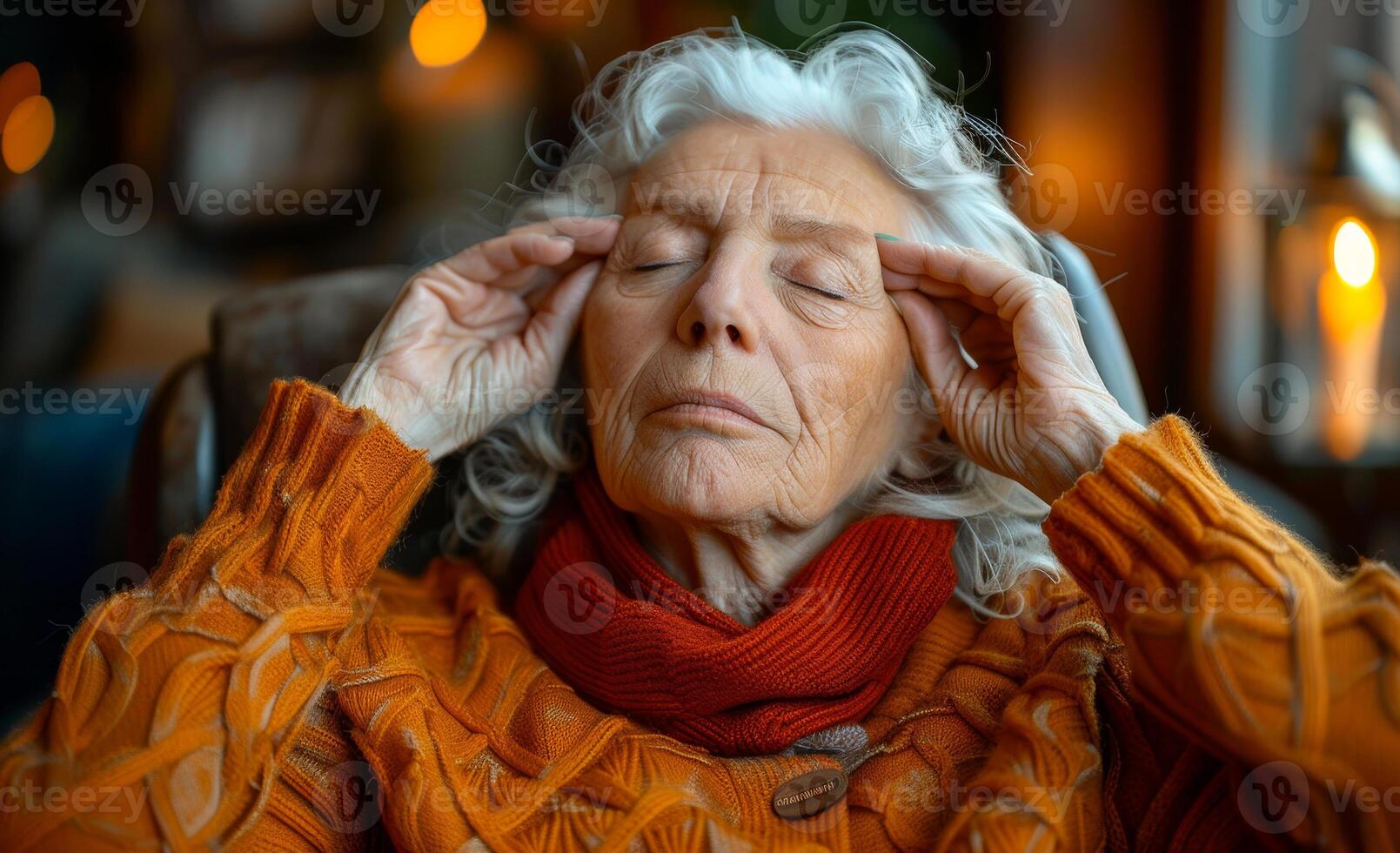 A woman is sitting in a chair with her hands on her head. She is wearing an orange sweater and a red scarf photo