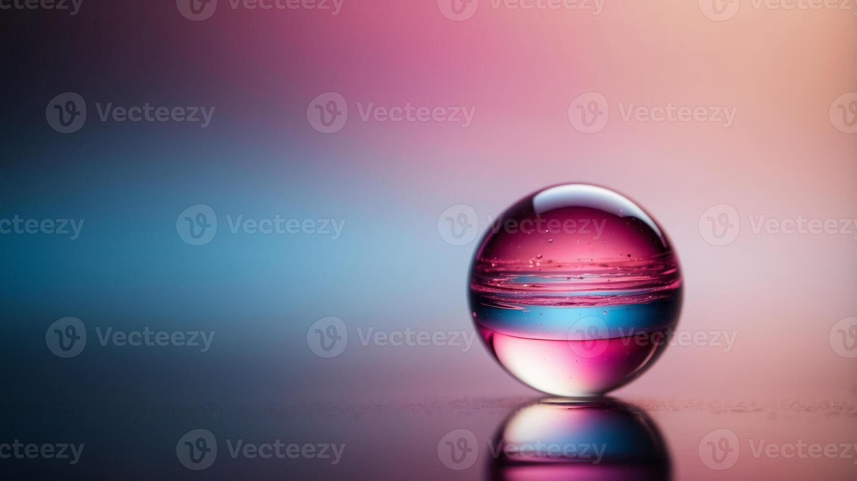 A colorful glass sphere on a reflective surface with a vibrant gradient background featuring pink and blue hues, creating a modern abstract aesthetic. photo