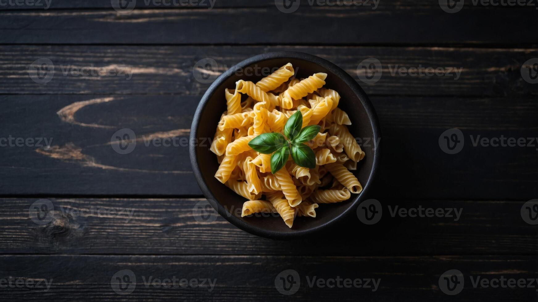 Top view of dry pasta on a black wooden surface typical of Italian cuisine creating a visually appealing copy space image. photo