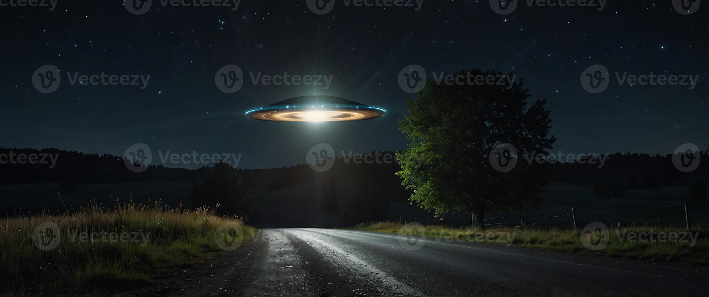 A glowing UFO hovers over a rural road at night. photo