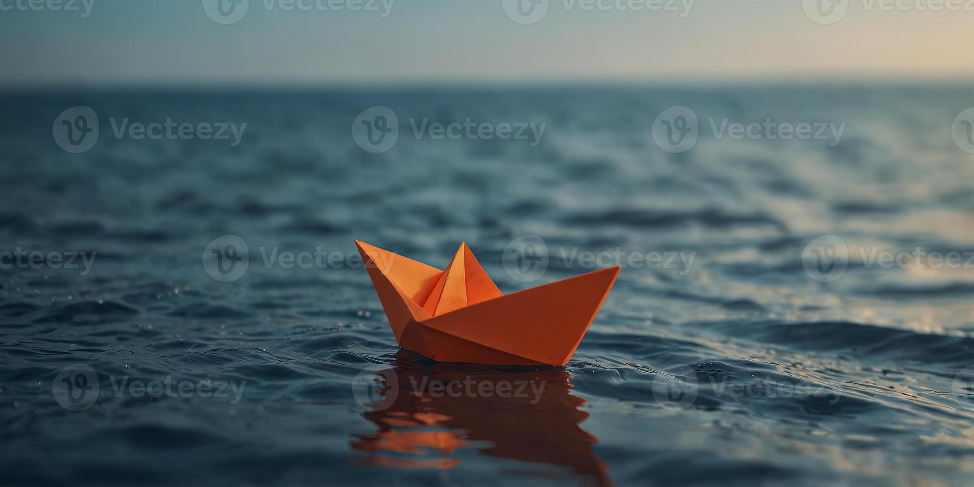 Orange paper boat floating on calm blue ocean. photo