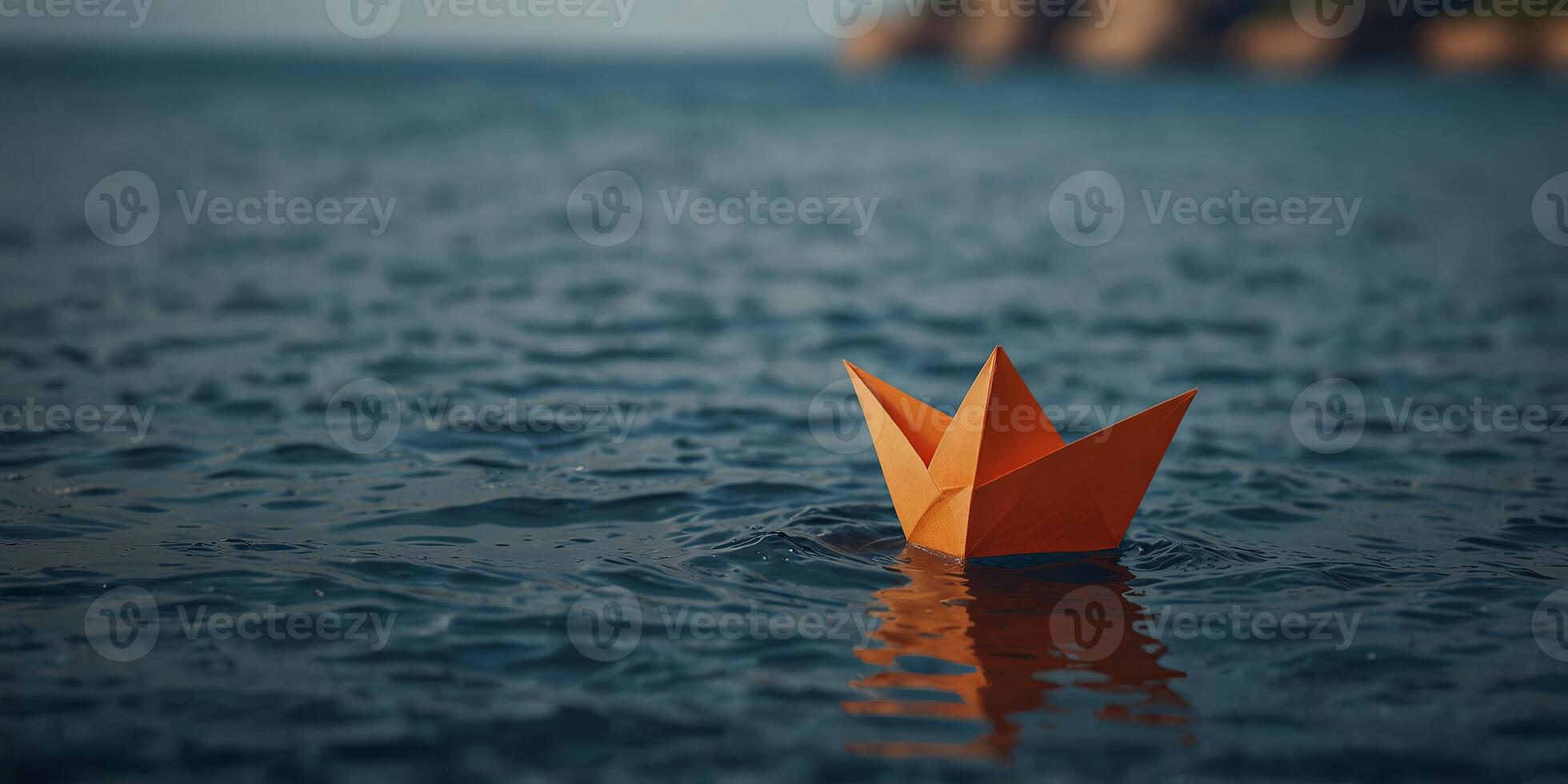 Orange paper boat floating on calm blue ocean. photo
