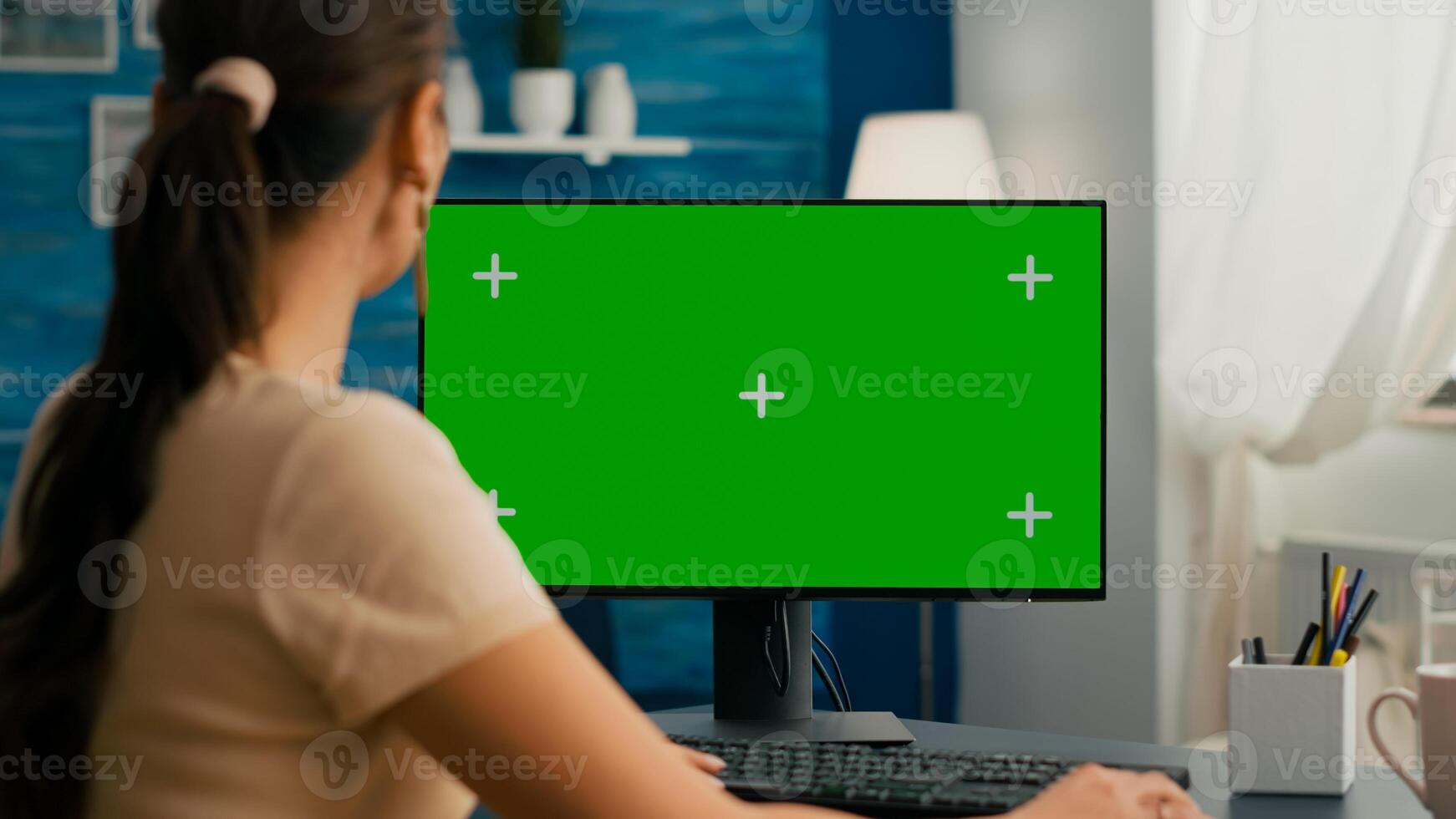 Woman sitting at office desk and searching on internet for commerce business using computer with mock up green screen chroma key. Caucasian female working with isolated pc photo