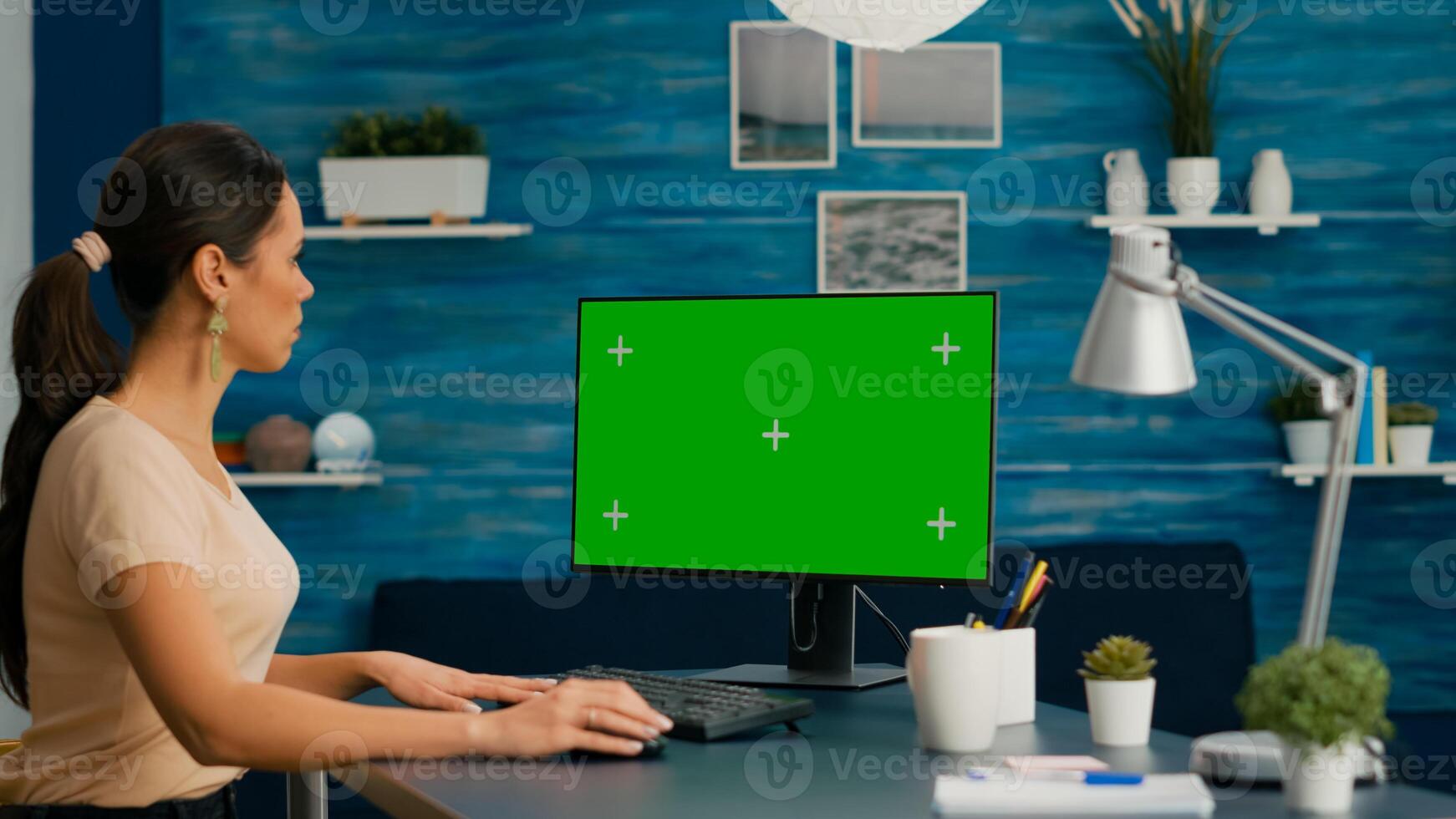 Woman working on personal computer with mock up green screen chroma key display in home office room. Caucasian female on isolated pc for project company photo