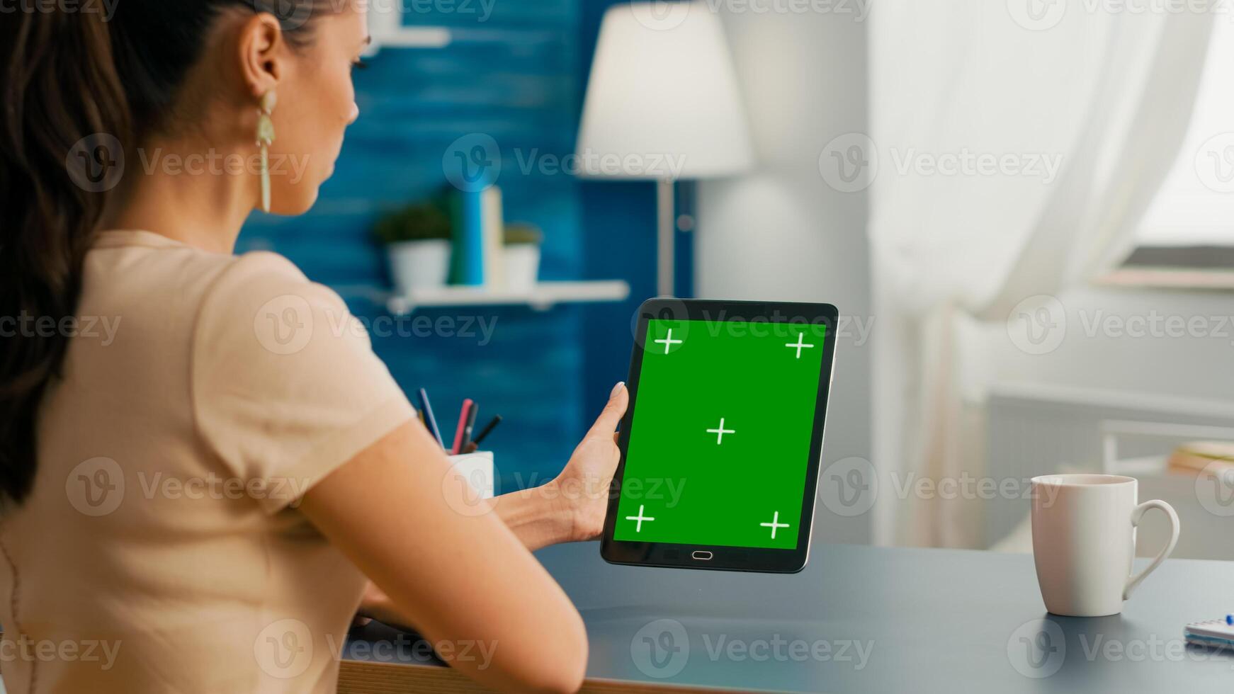 Freelancer woman working on communication ideas for online project using tablet computer with mock up green screen chroma key display. Office room in equipped with powerful isolated device photo