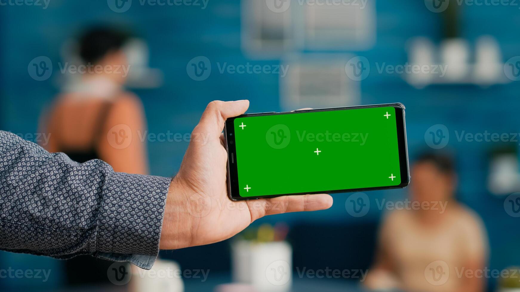 Front view of horizontal isolated mock up green screen chroma key display of modern smartphone. Business woman using isolated phone for browsing social networks sitting on office desk photo