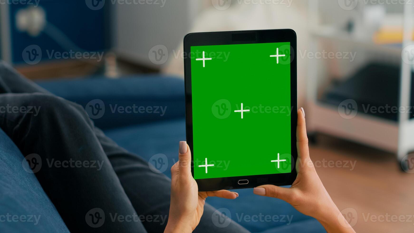 Close up of business woman hands holding tablet computer with mock up green screen chroma key display sitting on sofa. Freelancer using isolated touchscreen device for social networks browsing photo