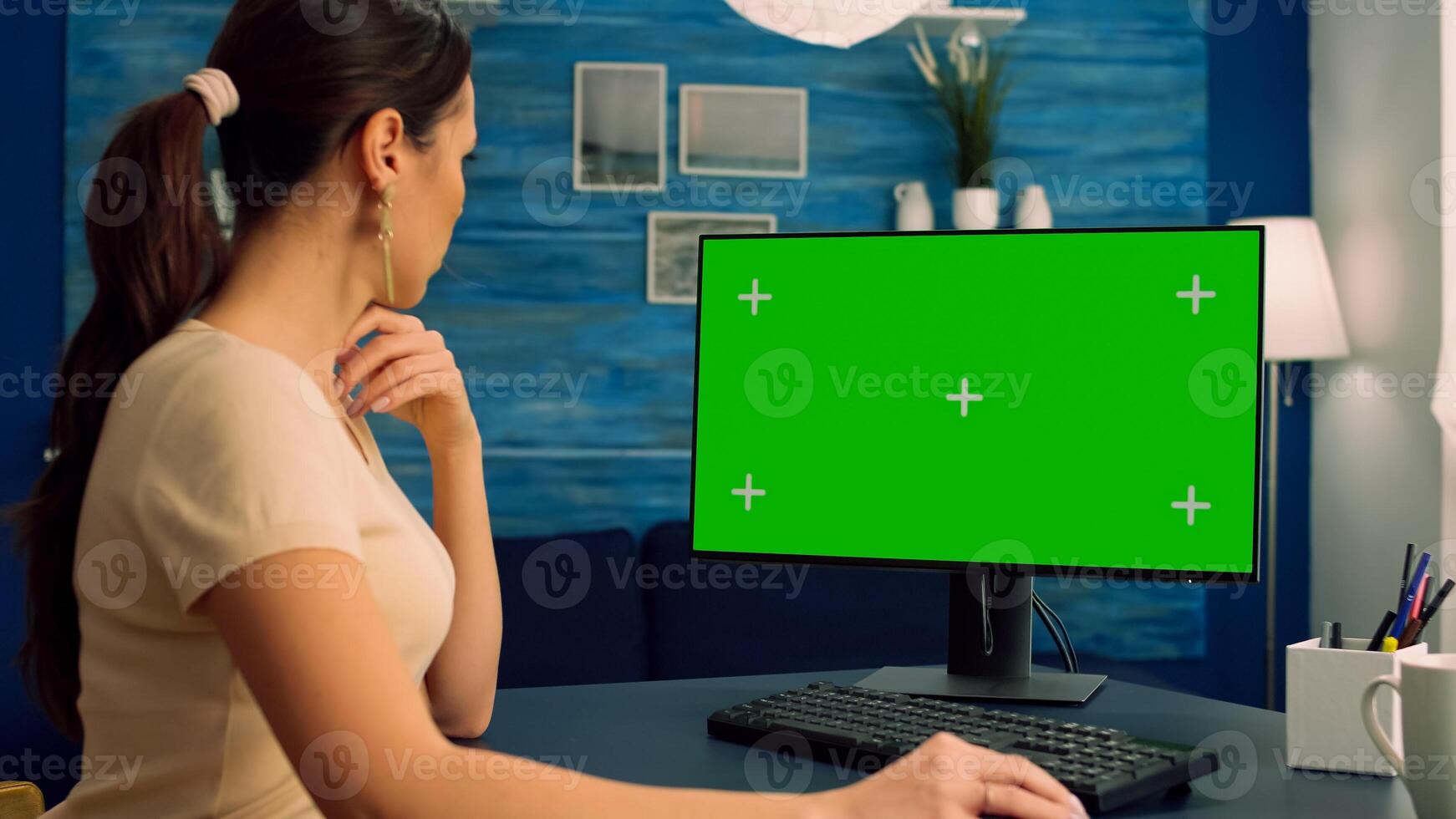 Caucasian female searching on computer with mock up green screen chroma key display browsing on internet for business communication sitting at desk table. Freelancer using isolated pc in home office photo