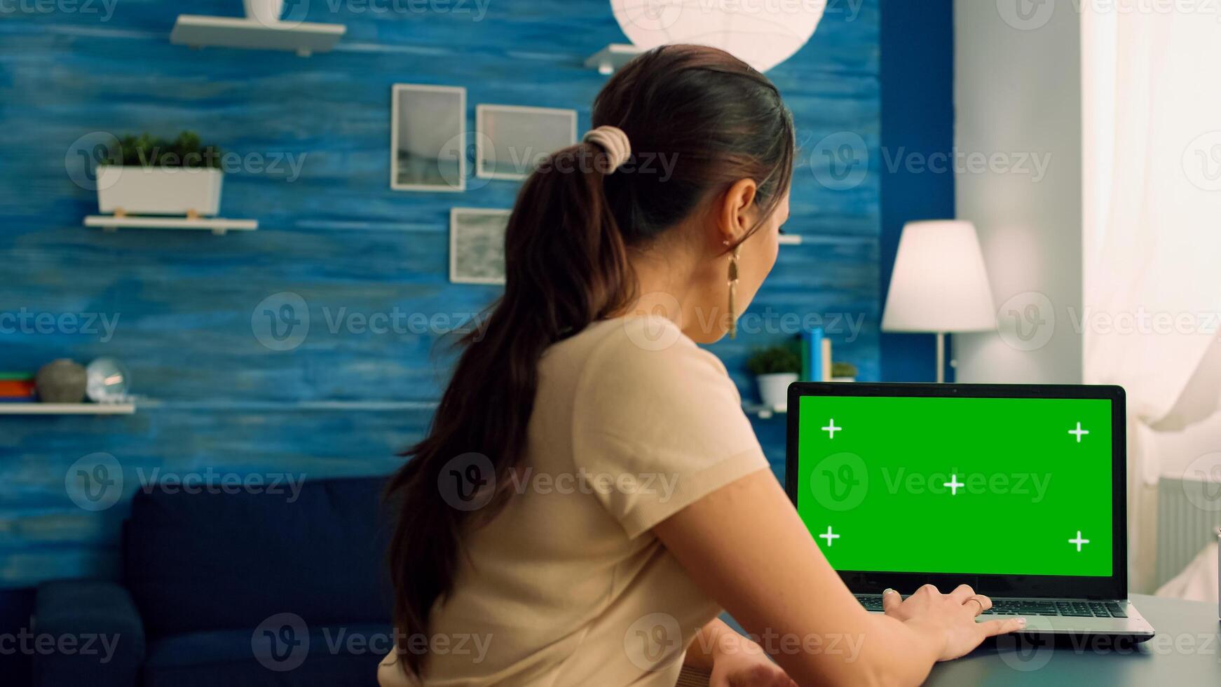 Caucasian female working on laptop computer with mock up green screen chroma key display for personal business. Woman typing on isolated pc sitting at desk table in office home photo