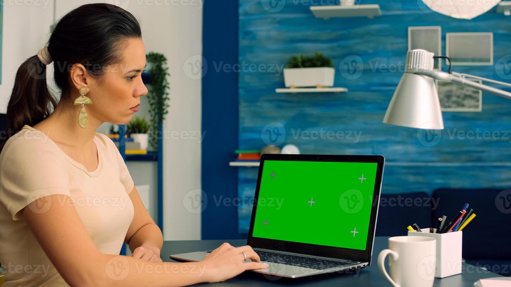 Business woman working at online coomunication project using laptop computer with mock up green screen chroma key display. Caucasian female standing on table desk working with isolated pc photo