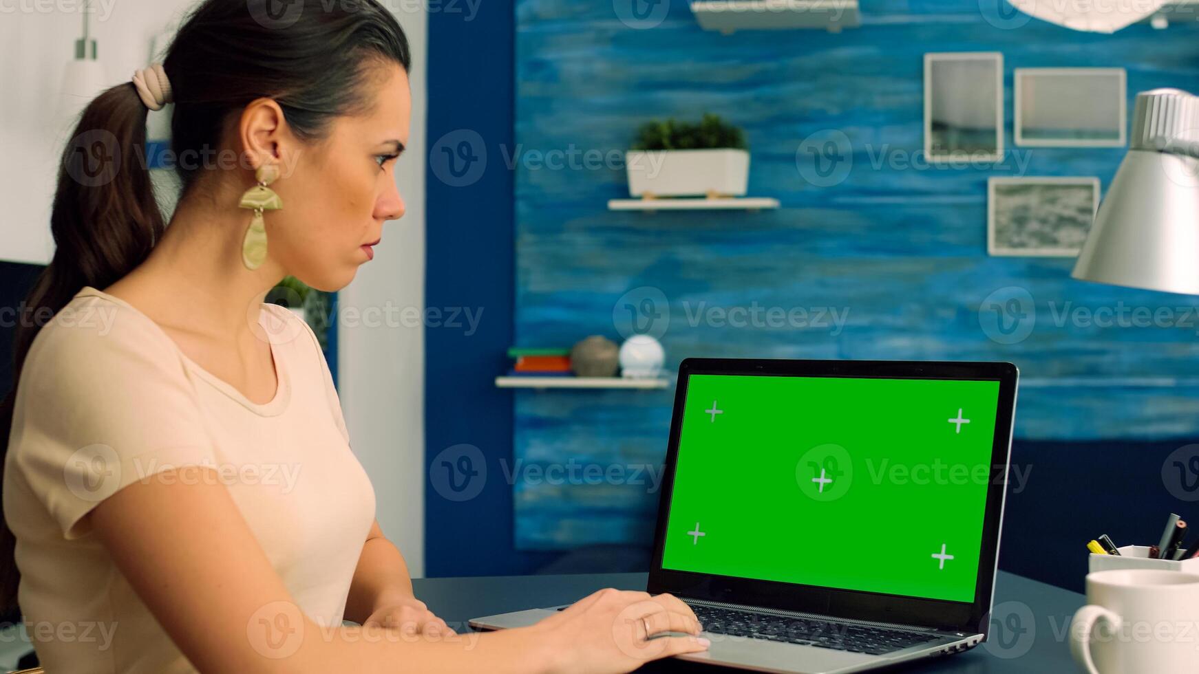 Business woman working at marketing project from home office using laptop computer with mock up green screen chroma key display. Freelancer typing isolated pc sitting at desk table photo