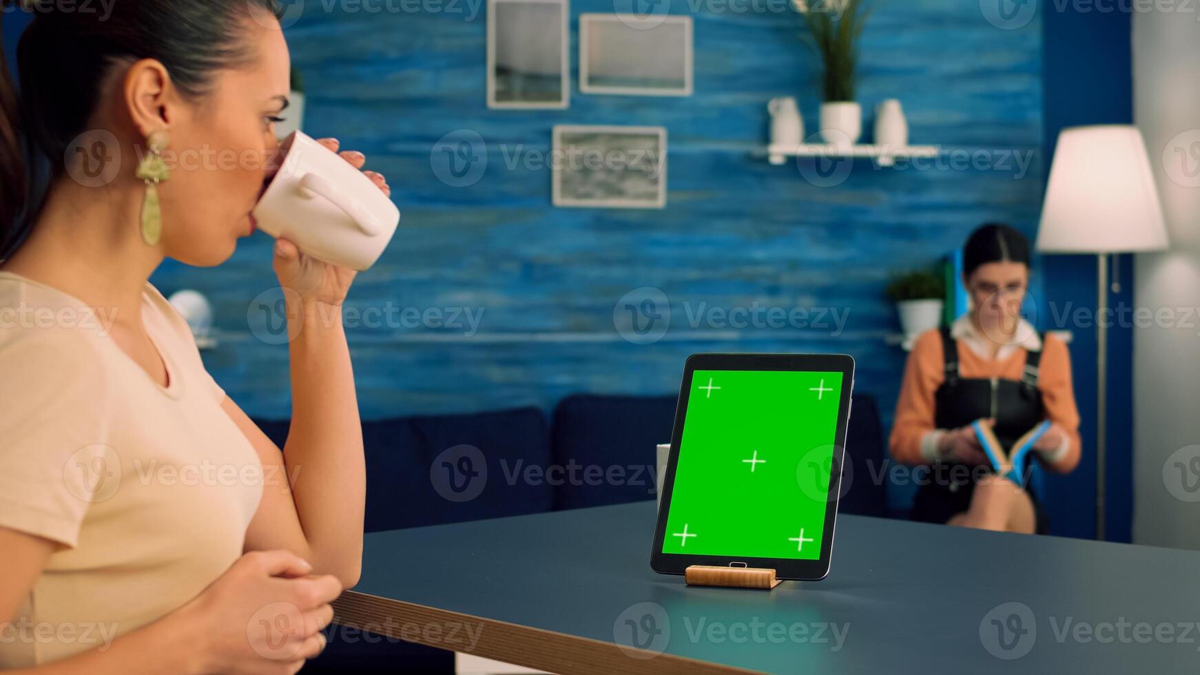 Freelancer woman browsing on internet business advertising using isolated device standing in home office studio. Caucasian female working with tablet computer with mock up green screen chroma key photo