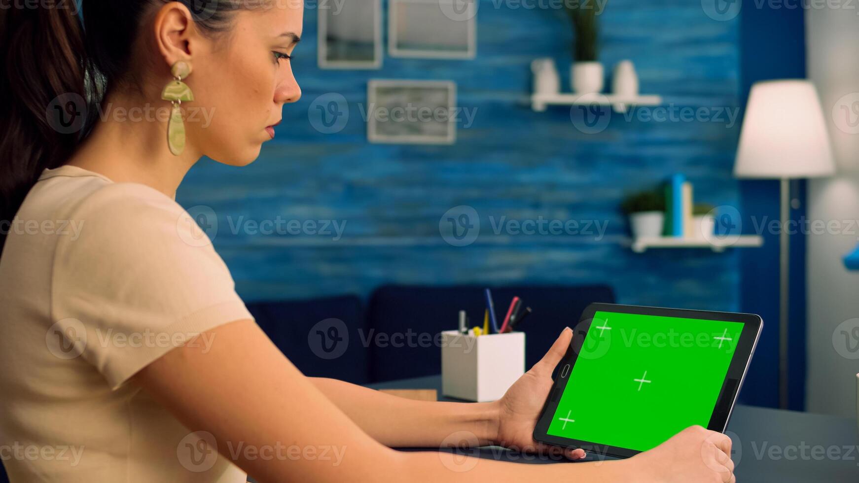Freelancer reading online book using tablet computer with mock up green screen display sitting at office desk. Caucasian woman looking at template chroma key isolated device using technology internet photo