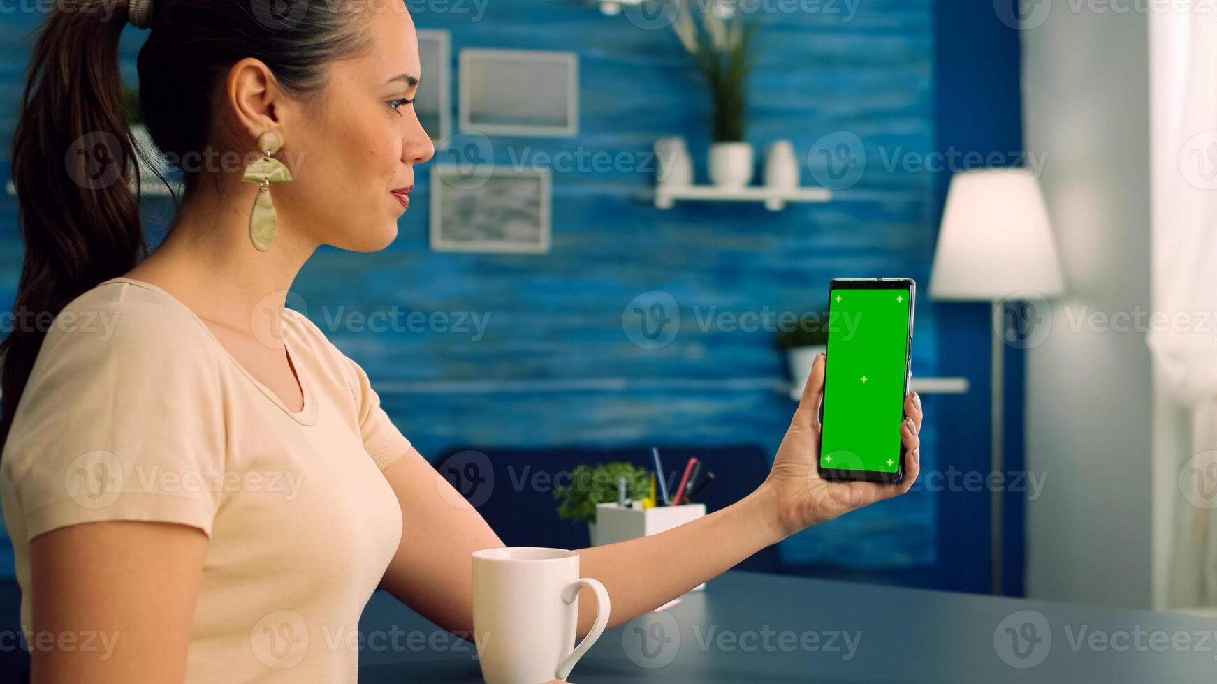 Freelancer using mock up green screen chroma key mobile during online videocall talking with her teamates about online app project standing on office desk. Business woman using isolated technology photo
