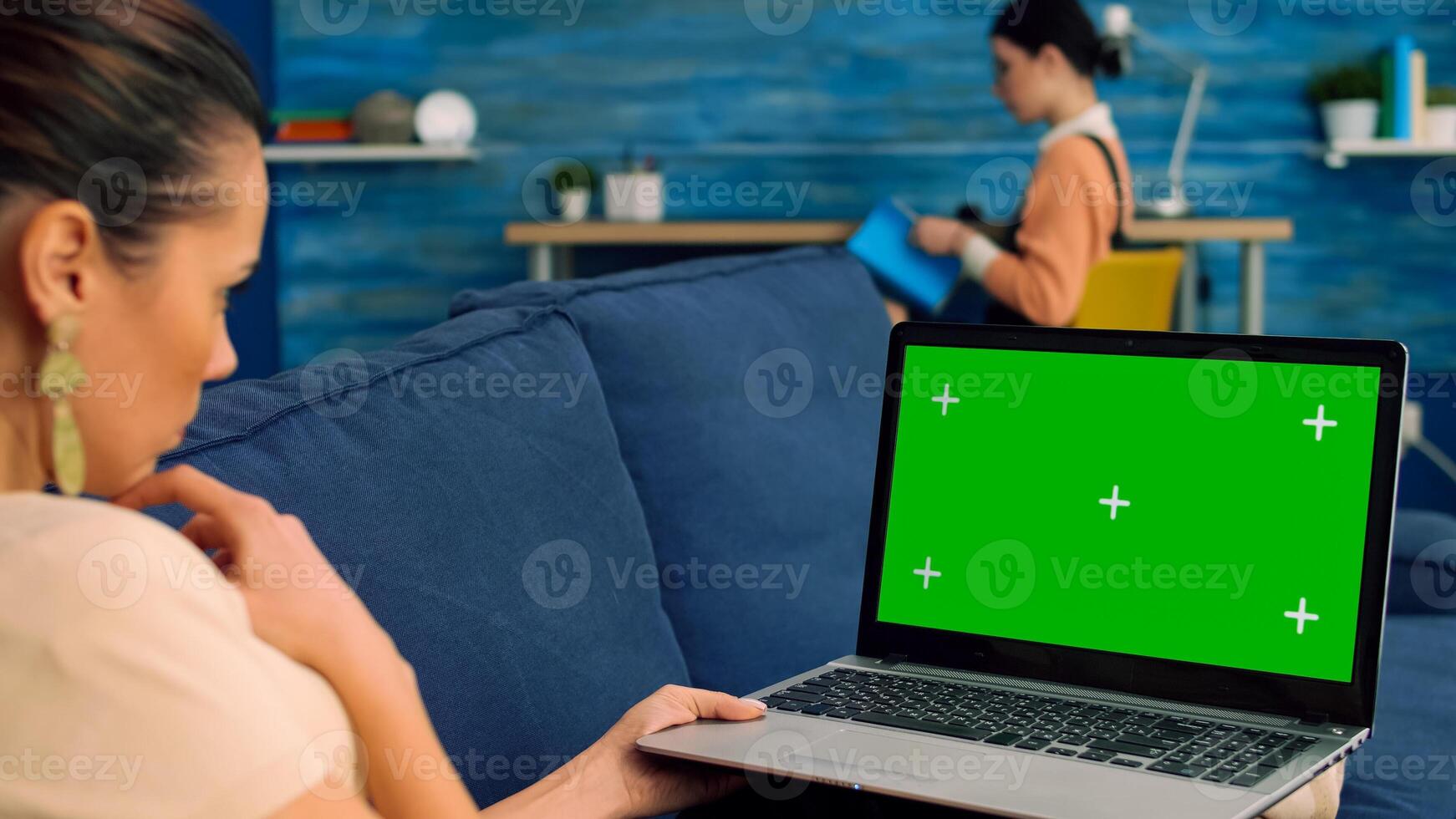 Business woman searching lifestyle advertising using isolated pc lying on sofa in living room. Caucasian female working with laptop computer with mock up green screen chroma key photo