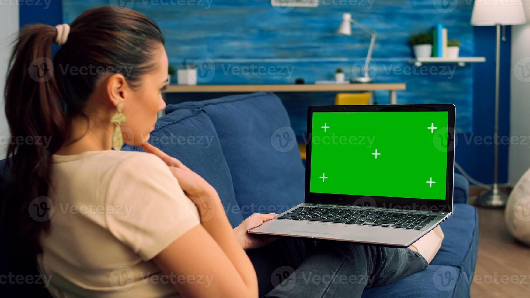 Back shot of caucasian female typing and looking at laptop computer with mock up green screen chroma key. Business woman searching the web for company information using isolated pc photo