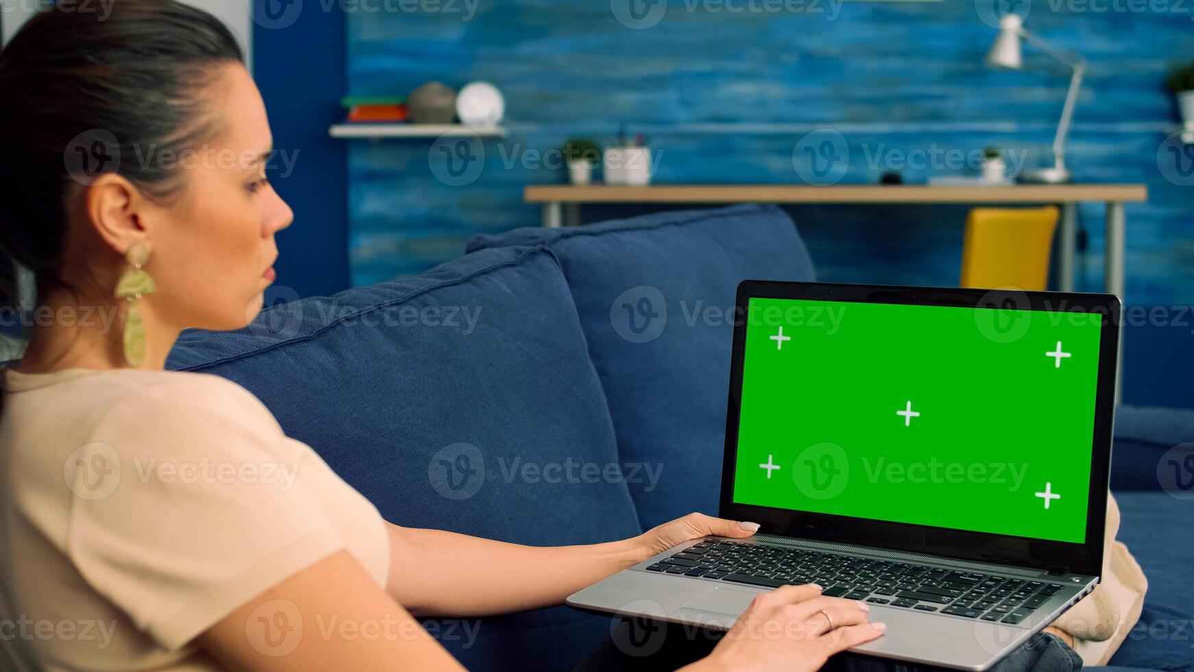 Freelancer using laptop computer with mock up green screen chroma key for online business standing sofa. Woman using isolated home office pc working at company project in living room photo