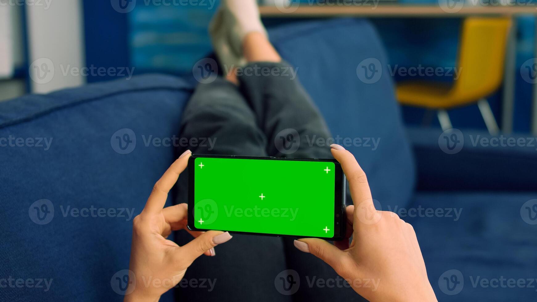 Business woman lying on sofa holding isolated phone with mock up green screen chroma key during social media media communication. Caucasian female browsing on internet watching online videos photo