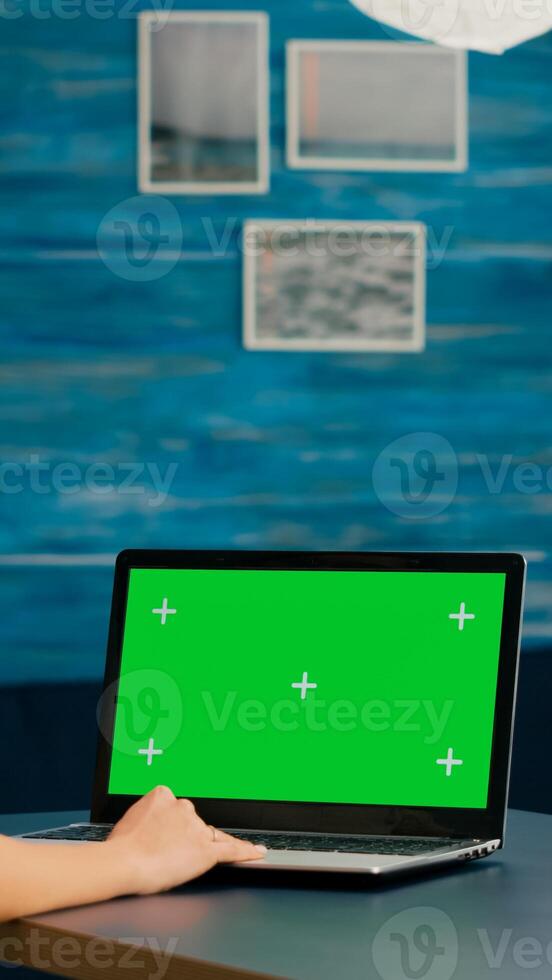 Freelancer using computer with mock up green screen chroma key for business company standing on desk table. Woman using isolated home office pc working at commerce project in home office photo