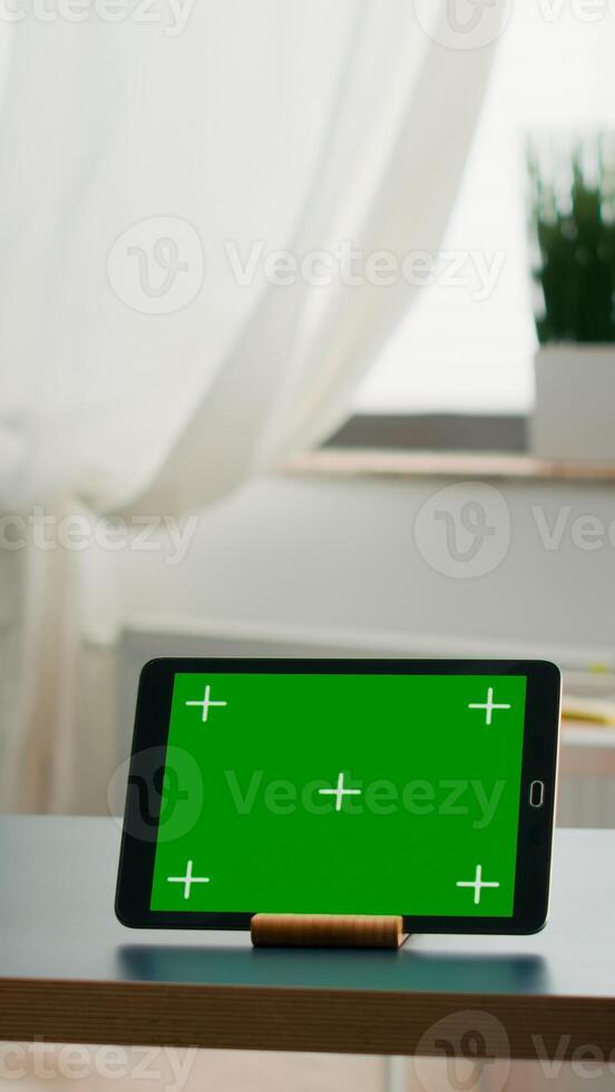 Two collegues talking about internet connection in front of tablet computer with mock up green screen chroma key. Women browsing on isolated device sittings at office desk in modern living room photo