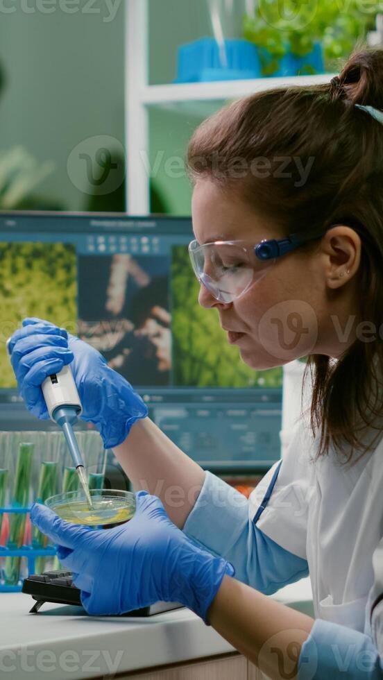 Chemist woman taking dna liquid from test tube with micropipette putting in petri dish analyzing genetic mutation. Biologist researcher working in pharmaceutical laboratory photo