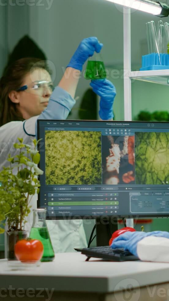 Scientist woman typing microbiology expertise on computer for scientific agriculture experiment. Medical team working with vegetables and fruit discovering genetic mutation in farming laboratory photo