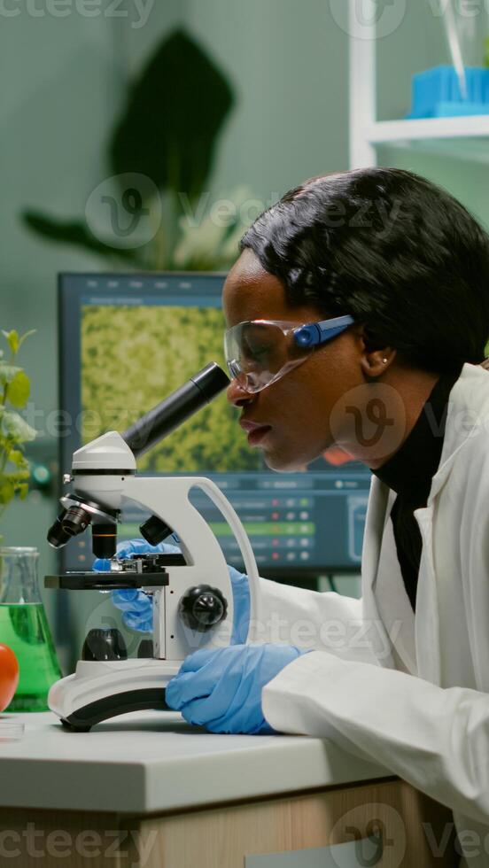 Biologist woman examining biological slide for medical expertise using microscope. Chemist scientist analyzing organic agriculture plants in microbiology scientific laboratory photo