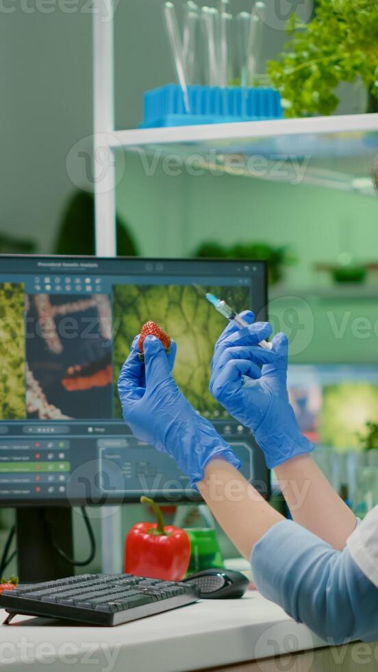 Scientist injecting strawberry with pesticides discovery genetic mutation of fruits for organic experiment. Biochemist working in pharmaceutical laboratory testing health food for medical expertise photo