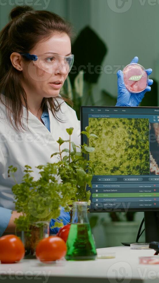 Two scientists talking about vegan meat sample typing biotechnology expertise on computer. Medical team researching vegetareian food modified genetically working in chemistry laboratory photo