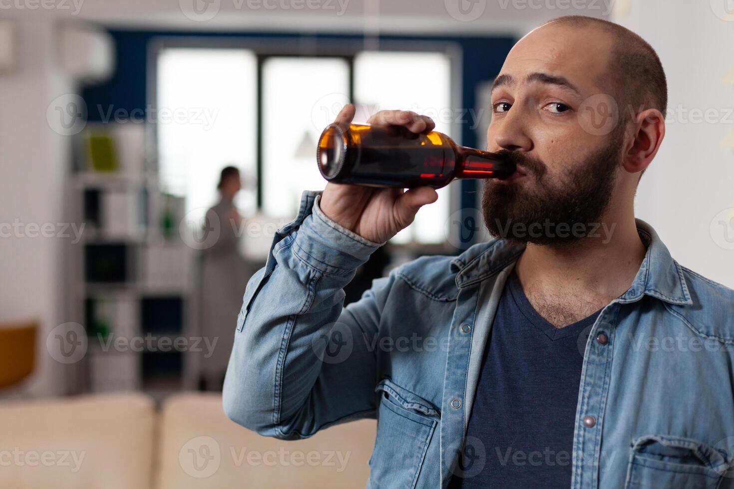 Portrait of caucasian man with bottle of beer at after work drinks meeting with coworkers. Person having fun with friends in business office, enjoying party celebration with food and alcohol. photo