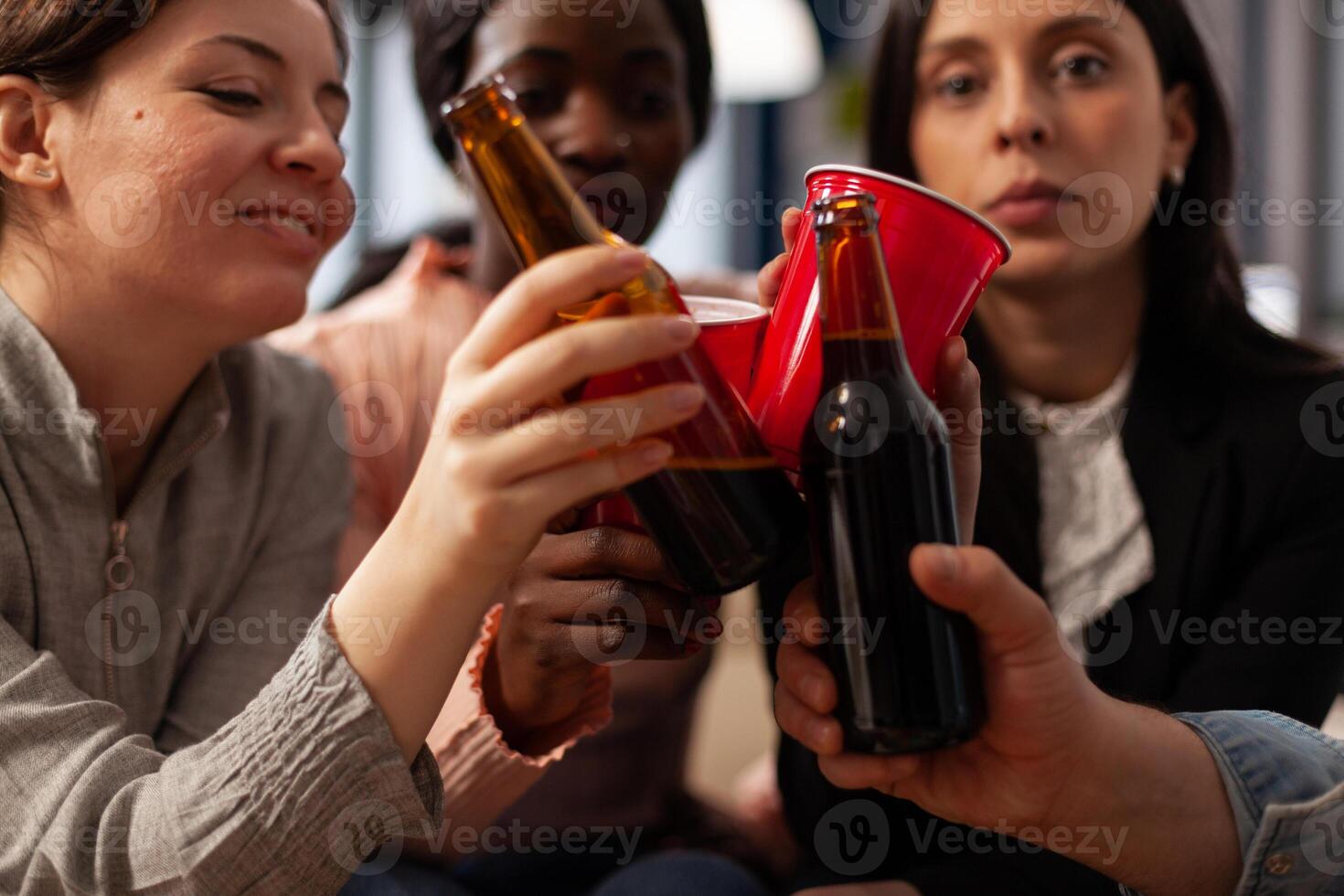 Business people clinking glasses and bottles of beer at office party celebration after work. Friends meeting to enjoy drinks after work, doing cheers gesture for celebration. Close up. photo
