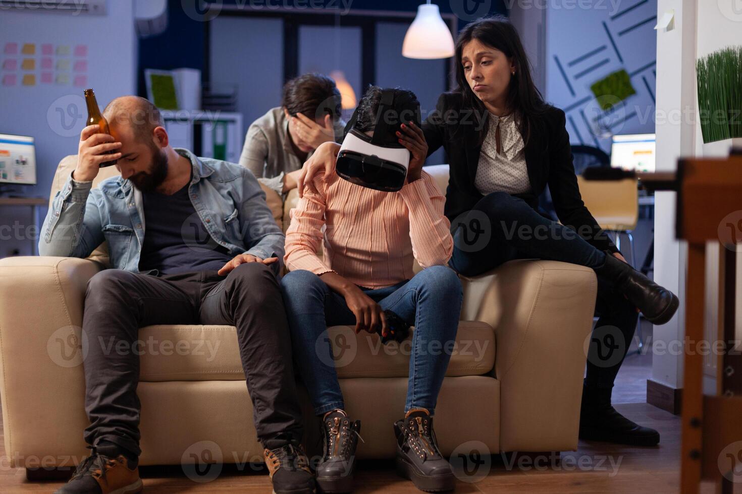 Disappointed woman with vr headset losing at games on tv console, using virtual reality glasses and controller to play for entertainment. Office colleagues meeting for drinks after hours. photo