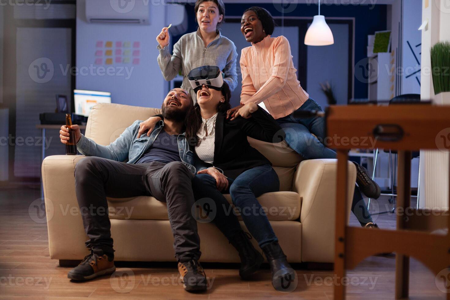 Coworkers feeling happy about games online win with vr goggles and controller. Cheerful people having fun with leisure activity at beer drinks celebration in office after hours. photo