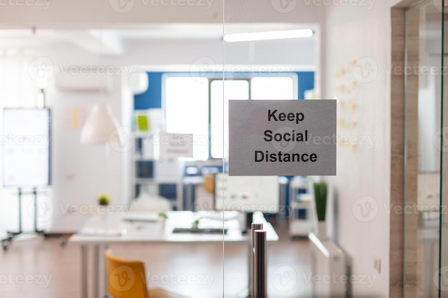 Keep Social Distance sign on glass wall in empty office during covid 19 coronavirus pandemic. Business workplace interior with nobody in it, economy crisis. photo