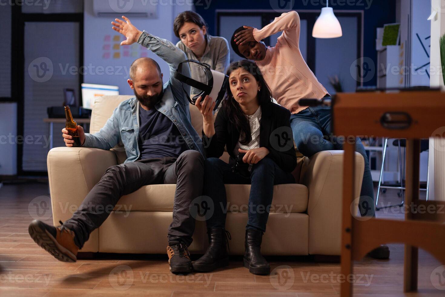 Frustrated coworkers losing at games online play, using online game play with vr glasses. Office colleagues feeling sad about lost game at celebration after work hours with beer. photo