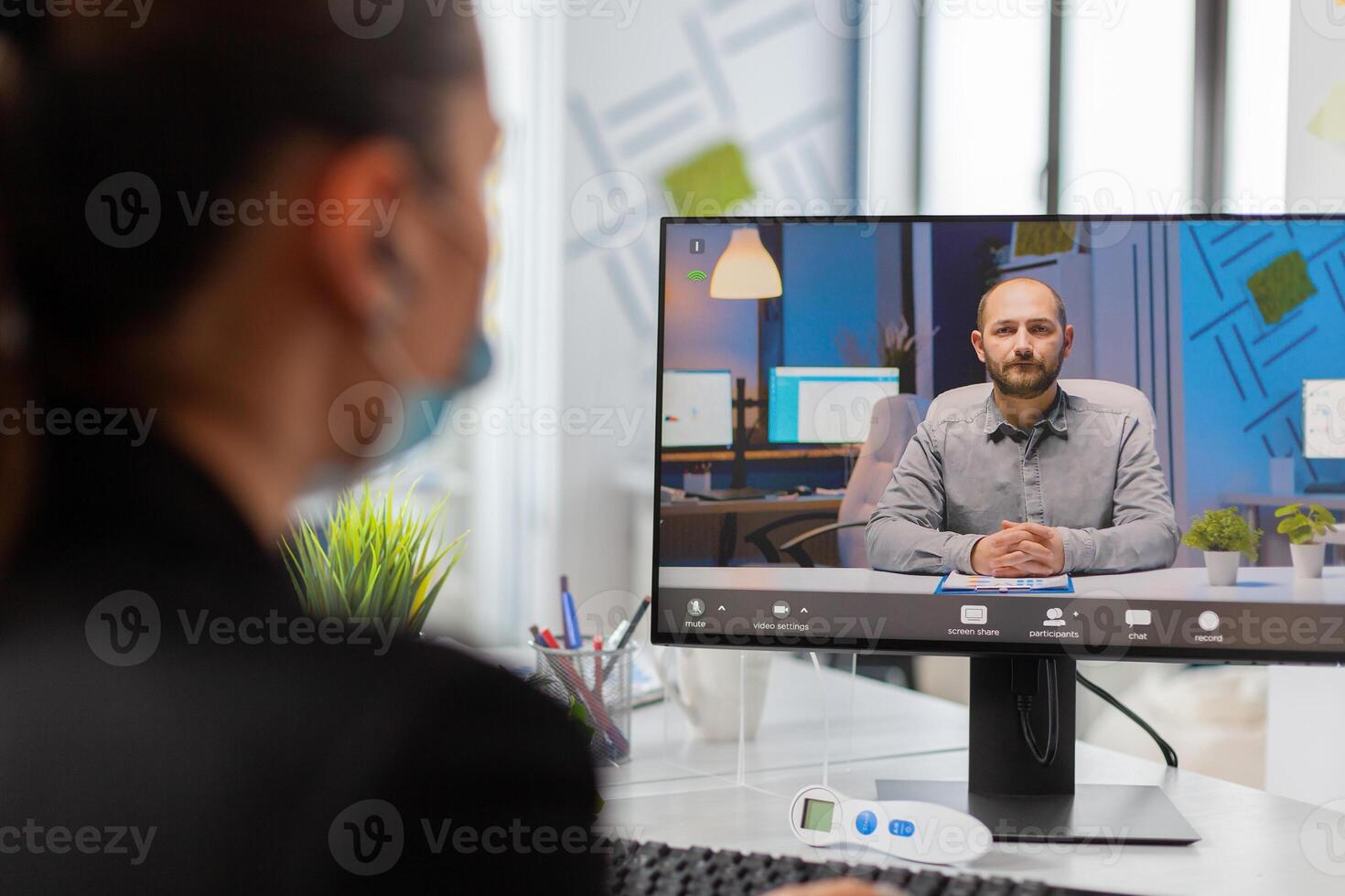 Back view of woman listening entrepreneur during remove call in new normal workplace, wearing face mask as prevention from infection with coronavirus during global pandemic. photo