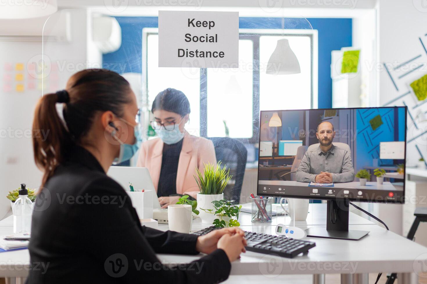 Coworkers discussing project during remote call from new workplace in time of global pandemic with coronavirus, wearing face mask as prevention to covid flu. photo