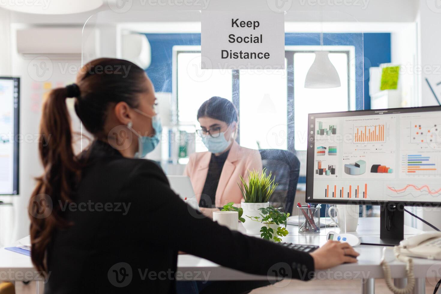 Teamwork wearing medical face mask to prevent infection with coronavirus working at marketing strategy in startup corporate office. Manager planning partnership presentation. Financial graph on screen photo